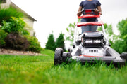 Photo of Craftsman lawn mower CMCMWSP320X2 in use on grass lawn, close-up front view, user pushing mower outdoors.